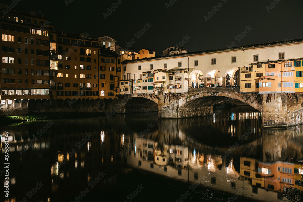 ponte vecchio florence italy by night. Lights in darkness and reflections on the water.