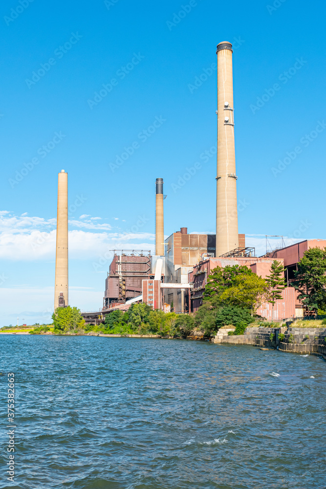 Abandoned factory on waterfront in bay with smokestacks