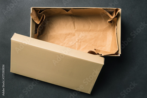 Open empty box with a lid, isolated on a black background. Cardboard box for shoes or gift. Top view, flat layout photo