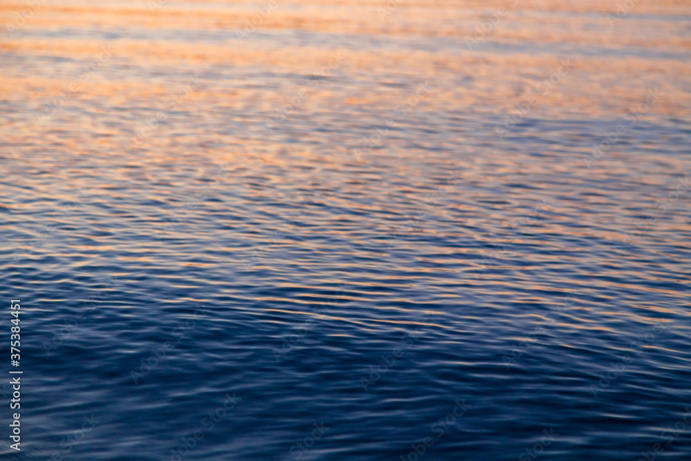 Clear water texture in blue and orange. Background of the ocean and the sea backlit by the sun. Natural water Clear water texture in blue and orange. Background of the ocean and the sea backlit by the sun. Natural water