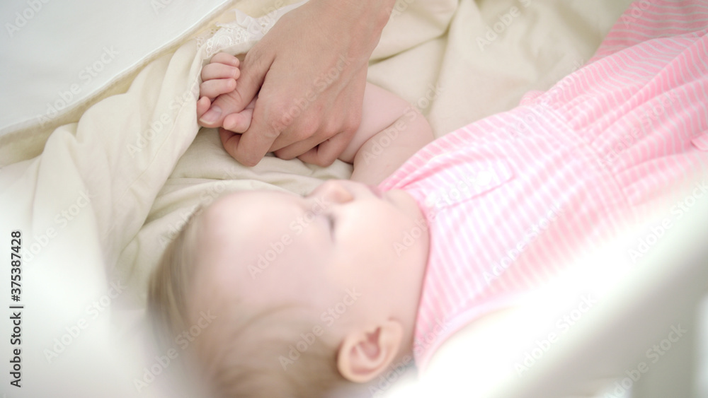 Little girl sleeping in bed. Mother hand stroking sleeping child Little girl sleeping in bed. Mother hand stroking sleeping child