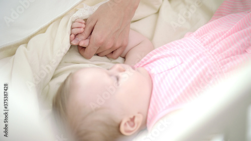 Little girl sleeping in bed. Mother hand stroking sleeping child