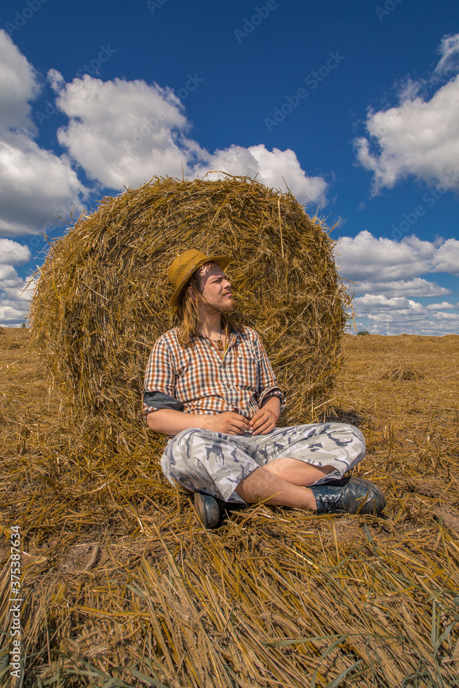 A young bearded man in cowboy hat with wheat roll A young bearded man in cowboy hat with wheat roll