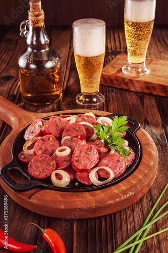 Sliced smoked fried calabrese sausage with onion and beer - Brazilian appetizer