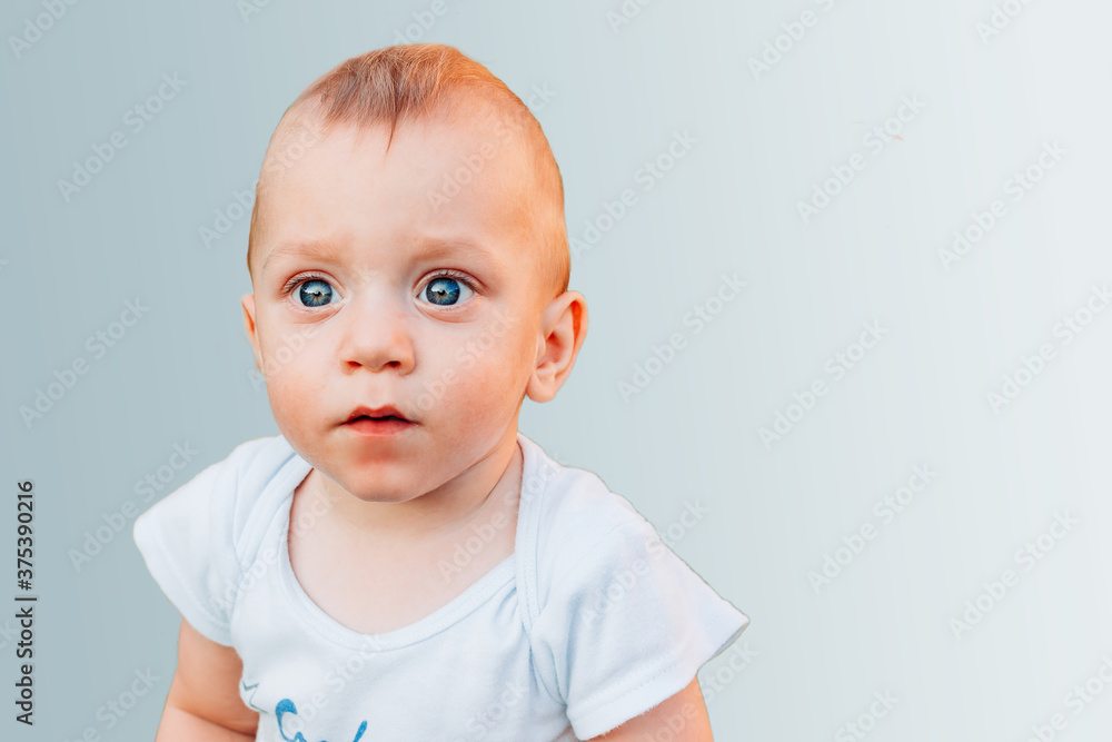 Beautiful one year old baby boy with blue eyes isolated on blue background Beautiful one year old baby boy with blue eyes isolated on blue background