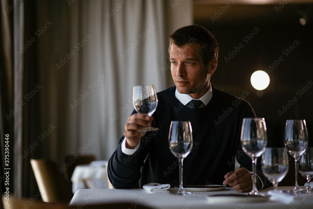 Handsome businessman dressed in the suit drinking wine. Businessman enjoying in the restaurant.. Handsome businessman dressed in the suit drinking wine. Businessman enjoying in the restaurant..