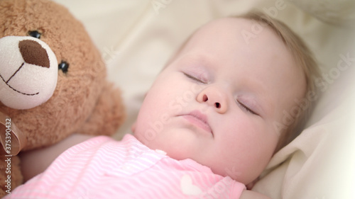 Adorable baby sleeping in bed. Portrait of sleeping baby with toy bear