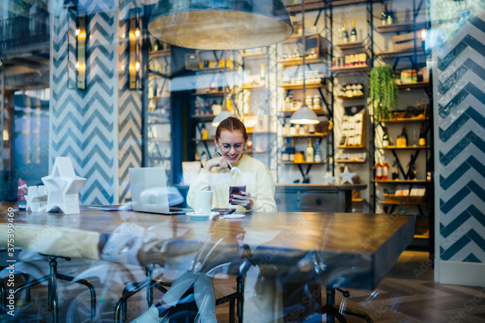 Cheerful woman browsing smartphone in cafe