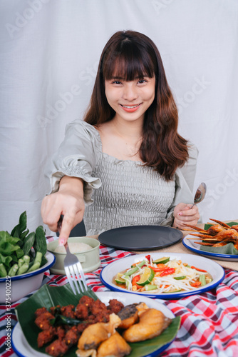 Portrait of asian woman using fork eating spicy pork ball on table.