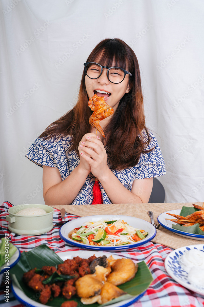 Portrait of young asian woman eating roasted chicken wing with happy looking. Portrait of young asian woman eating roasted chicken wing with happy looking.
