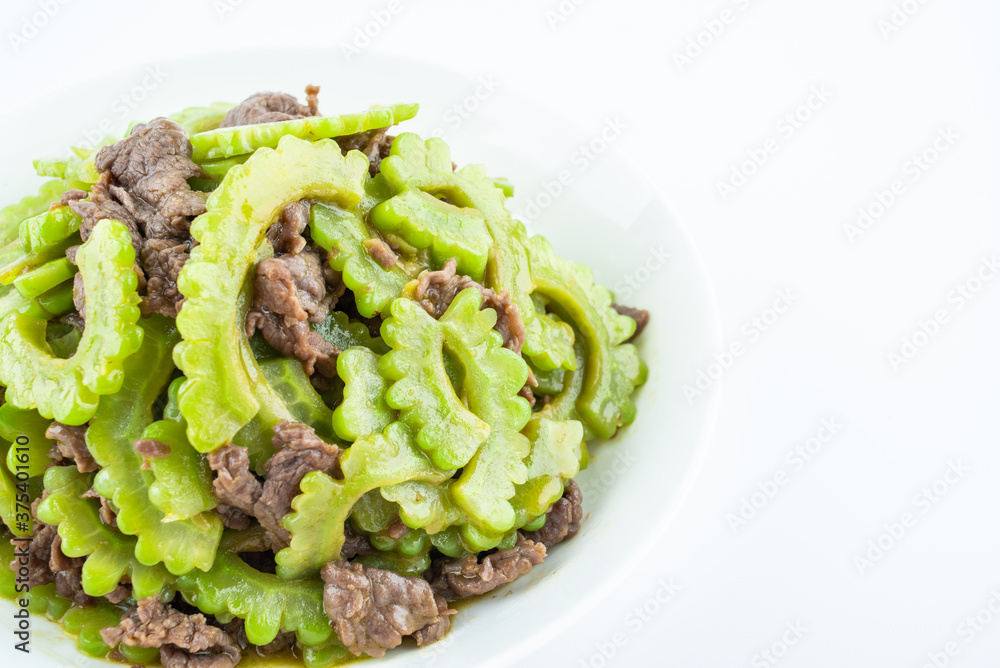 Stir-fried beef with bitter gourd on a plate on white background Stir-fried beef with bitter gourd on a plate on white background