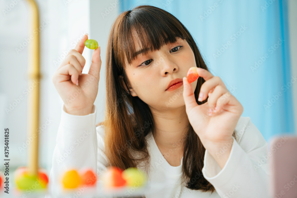 Portrait of young asian dark hair woman picking pastel fruit shaped mung bean. Portrait of young asian dark hair woman picking pastel fruit shaped mung bean.