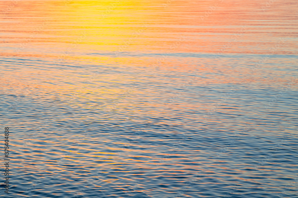Clear water texture in blue and orange. Background of the ocean and the sea backlit by the sun. Natural water Clear water texture in blue and orange. Background of the ocean and the sea backlit by the sun. Natural water