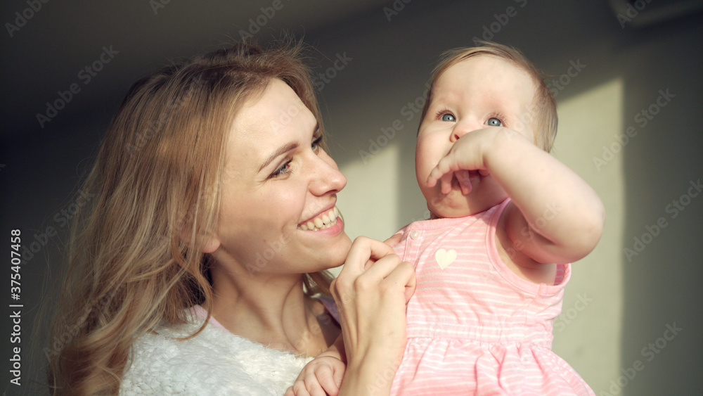 Happy mother holding baby girl on hands. Cheerful mom embrace toddler girl Happy mother holding baby girl on hands. Cheerful mom embrace toddler girl
