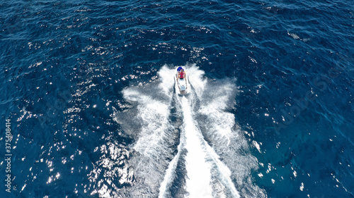 Aerial photo of woman operating jet ski cruising in low speed in deep blue crystal clear waters © aerial-drone