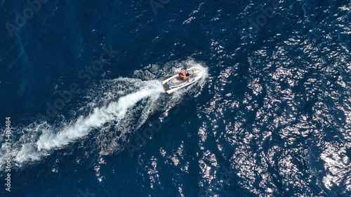 Aerial photo of woman operating jet ski cruising in low speed in deep blue crystal clear waters © aerial-drone