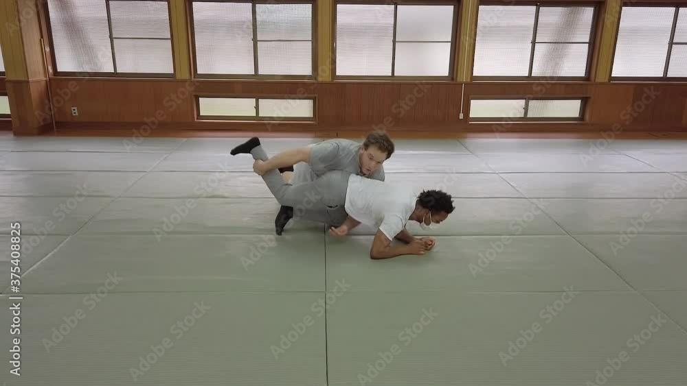 Ground restraint technique being demonstrated on gym floor vídeo de