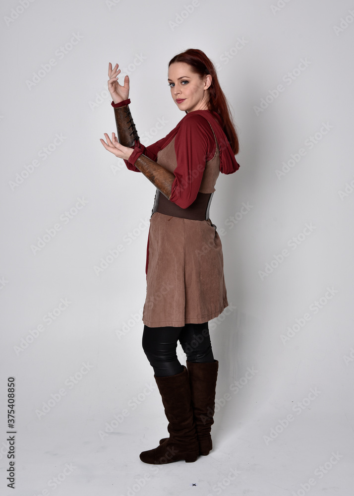 Full length portrait of girl wearing medieval costume. Standing pose with back to the camera, isolated against a grey studio background. Full length portrait of girl wearing medieval costume. Standing pose with back to the camera, isolated against a grey studio background.