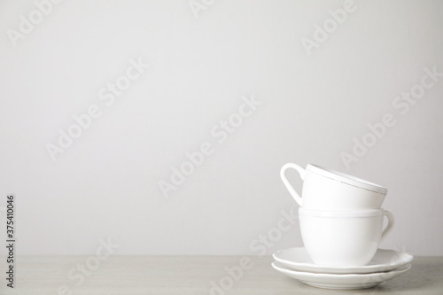 Ceramic saucers and cups on table against white background. Space for text