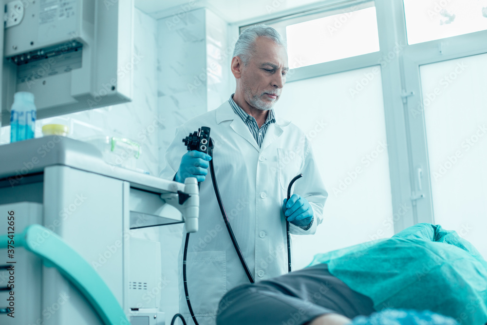 Serious medical worker getting ready for endoscopy procedure Serious medical worker getting ready for endoscopy procedure