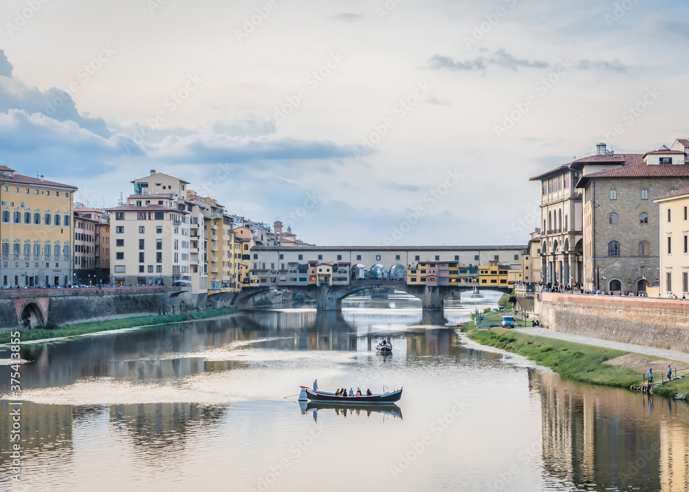 View of the river Arno, Ponte Vecchio bridge and pleasure boats in Florence in the evening in watercolor tones