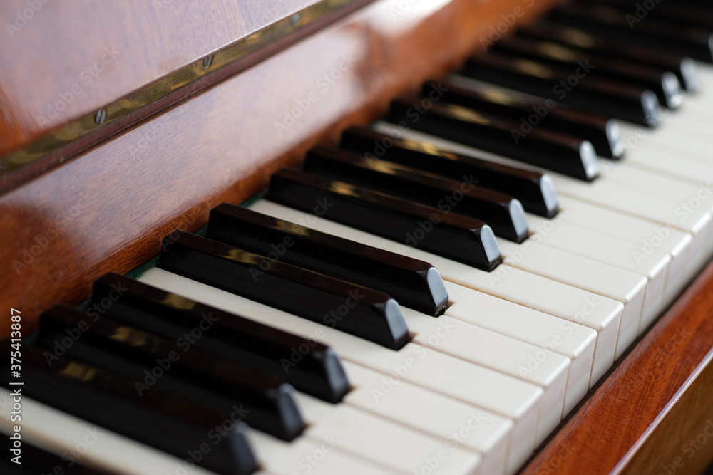 The keyboard of a brown upright piano on a blurred background. Selective focus. The keyboard of a brown upright piano on a blurred background. Selective focus.