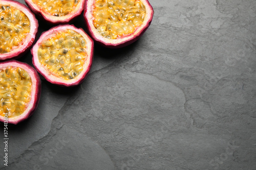 Halves of passion fruits (maracuyas) on black slate table, flat lay. Space for text