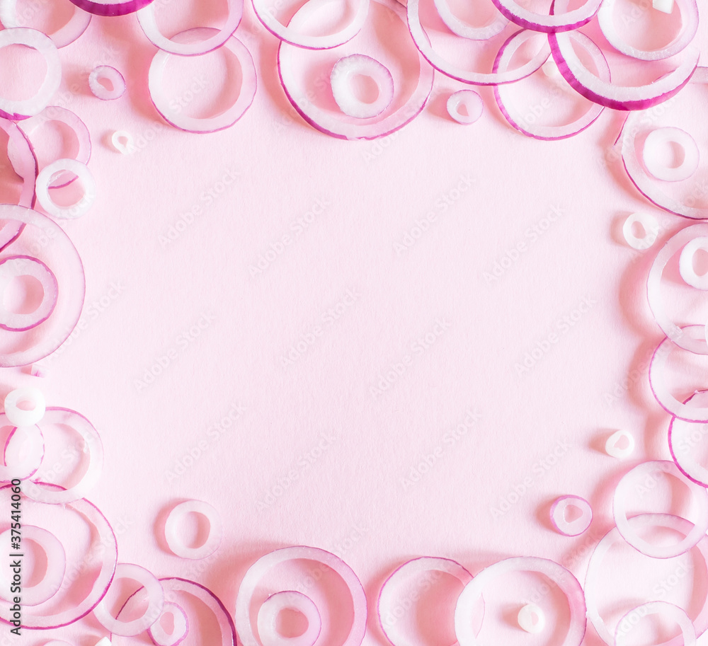 Decorative layout with red onion rings on a pink background, flatlay. The concept of minimalism in food photography.