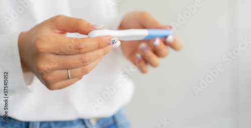 close up on adult woman hand holding pregnancy test kit and waiting result at home for family life concept
