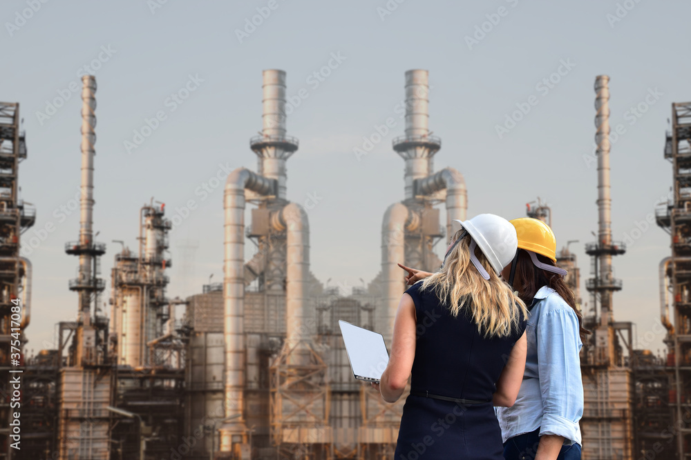 Businessman hand holding computer notebook on oil refinery industry plant, Petroleum energy concept Businessman hand holding computer notebook on oil refinery industry plant, Petroleum energy concept