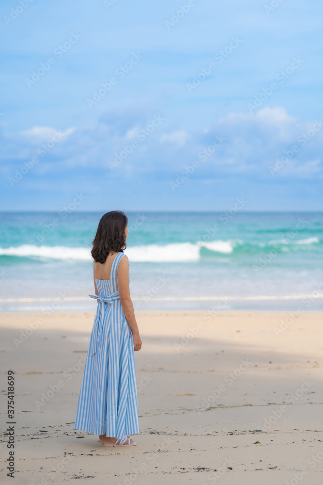 Full length of Woman in beautiful blue summer dress standing and looking to beach and sea blue sky horizon, vacation and travel ocean concept. Phuket, Thailand. Full length of Woman in beautiful blue summer dress standing and looking to beach and sea blue sky horizon, vacation and travel ocean concept. Phuket, Thailand.