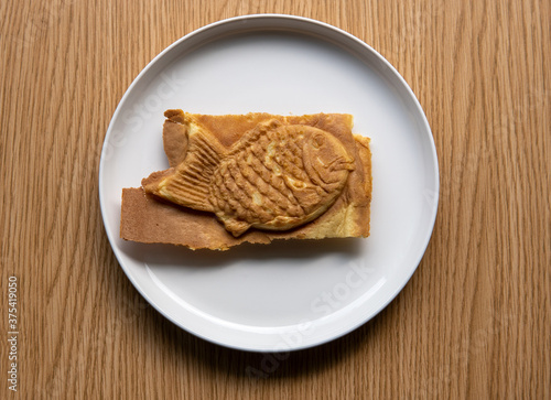 Taiyaki Japanese filled fish shaped pastry cake  on plate. Commonly filled with bean paste, custard, or sweet potato with a waffle like batter. (ID: 375419050)