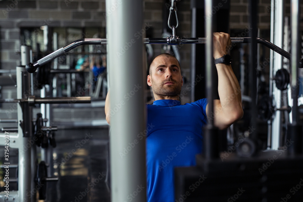Fit man exercising at the gym on a machine. Fit man exercising at the gym on a machine.