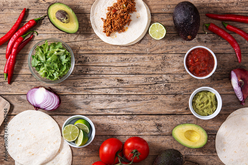 Mexican tacos ingredients on wooden table. Copy space