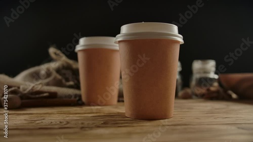 Two coffee special offer or promo, camera turning around. Two hands taking two drinks form wood desk. Brown disposable paper cups with copy space. Tea or coffee to go. Dolly shot. Slow motion
