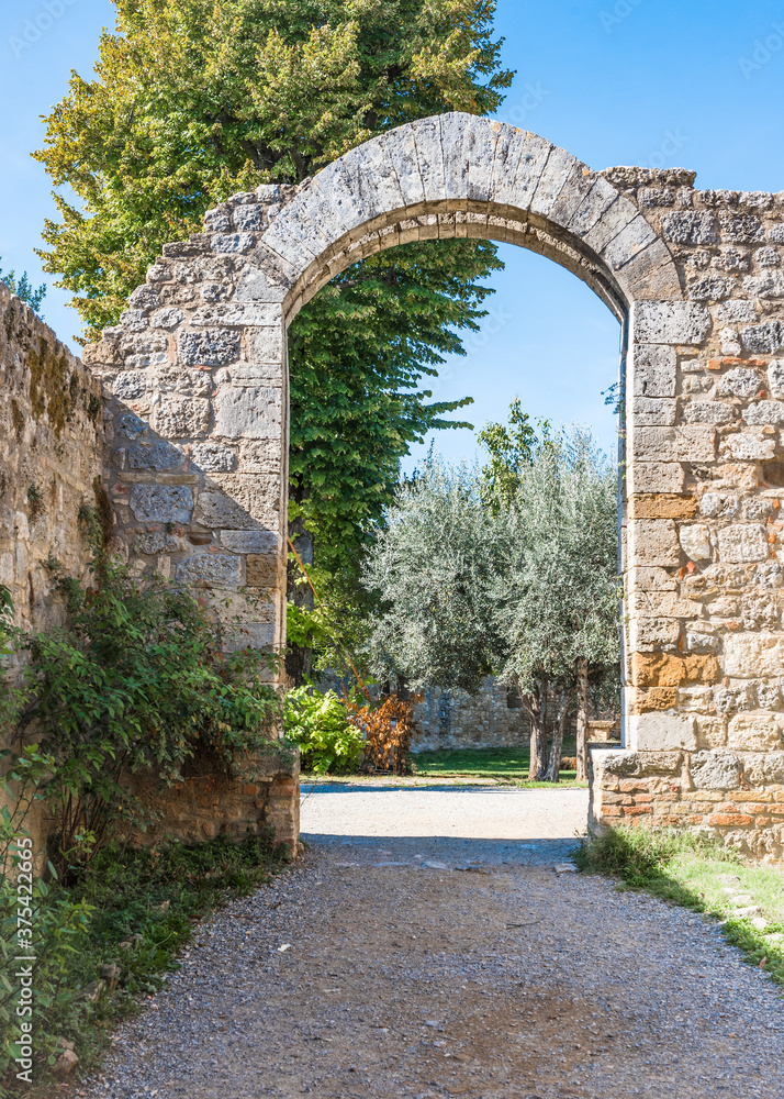 Old stone arch over the alley in the park in the Tuscan city of San Gimignano, Italy