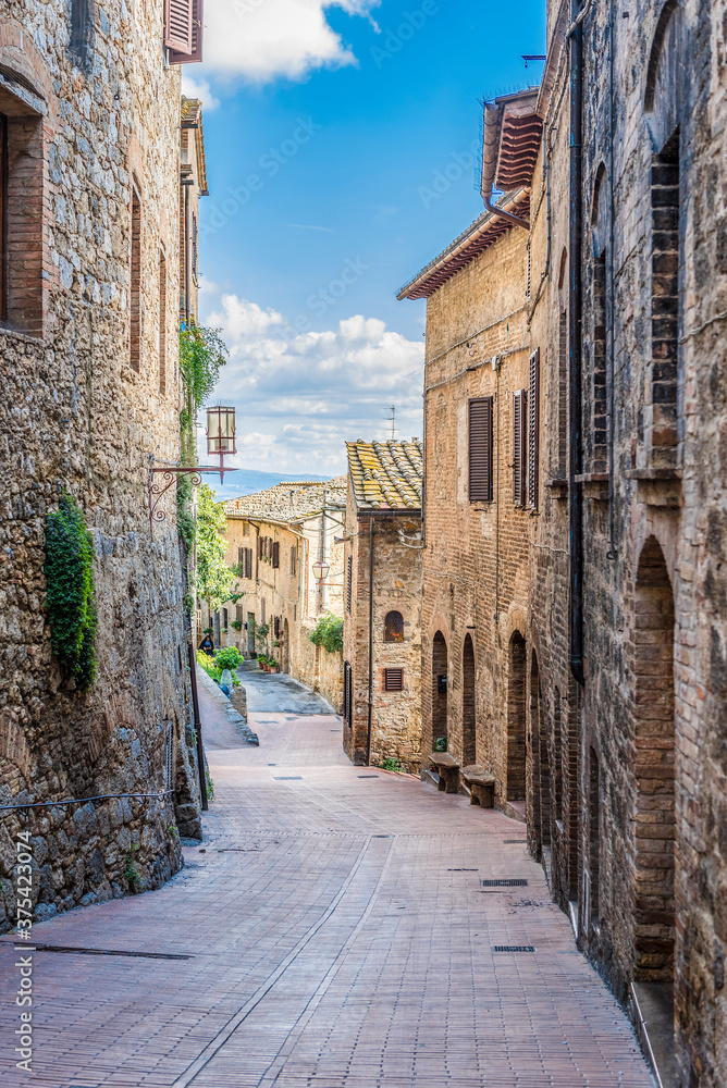 Narrow medieval street with lantern in San Gimignano, Italy