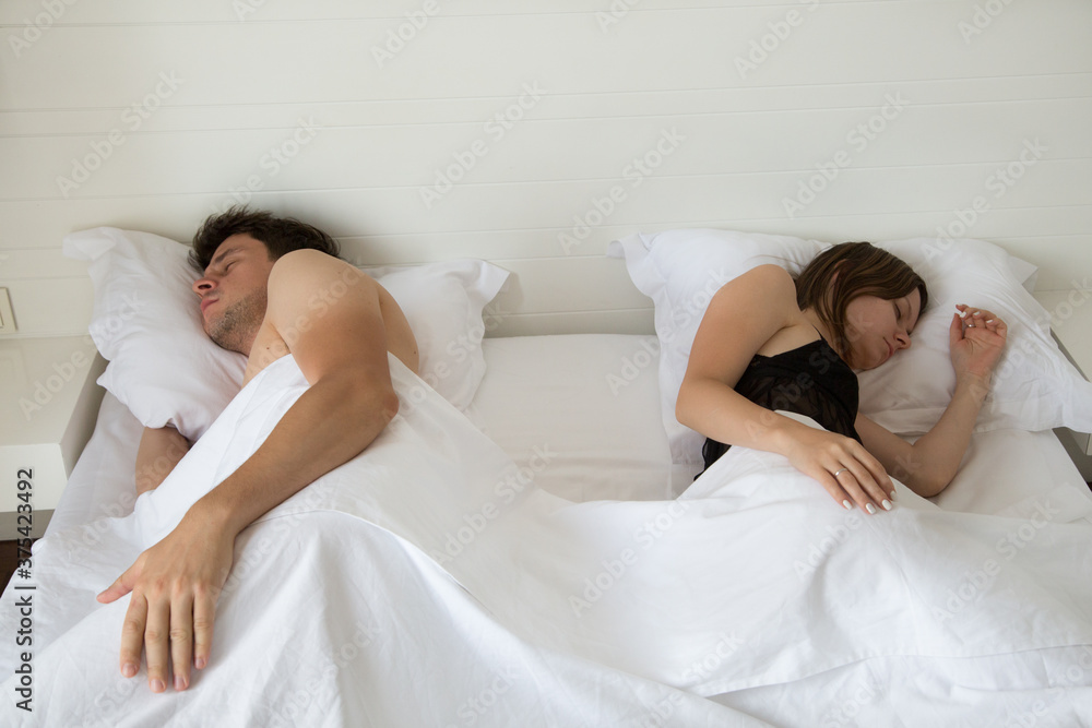 View from above on the young couple sleeping in their bed in the morning. View from above on the young couple sleeping in their bed in the morning.