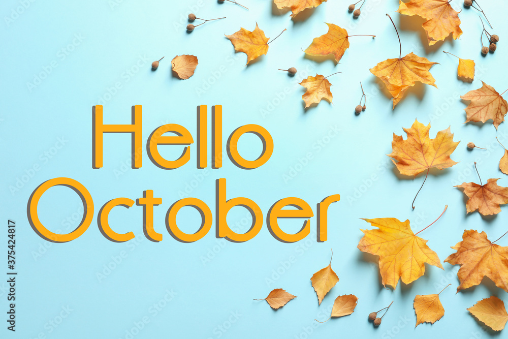 Text Hello October and golden autumn leaves on light blue background, top view Text Hello October and golden autumn leaves on light blue background, top view