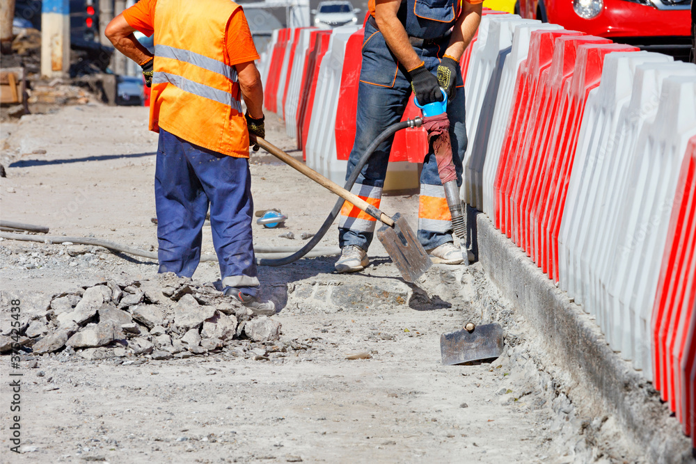 A team of workers cleans some of the concrete with a jackhammer and shovels during road repairs. A team of workers cleans some of the concrete with a jackhammer and shovels during road repairs.