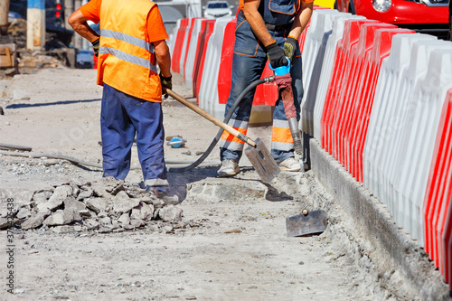 A team of workers cleans some of the concrete with a jackhammer and shovels during road repairs.