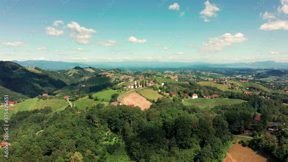 Aerial view of Austrian vilage Kitzeck in vineyard region of Styria. Tracked shoot of Church on the top of grape hill with alps in background. Aerial view of Austrian vilage Kitzeck in vineyard region of Styria. Tracked shoot of Church on the top of grape hill with alps in background.