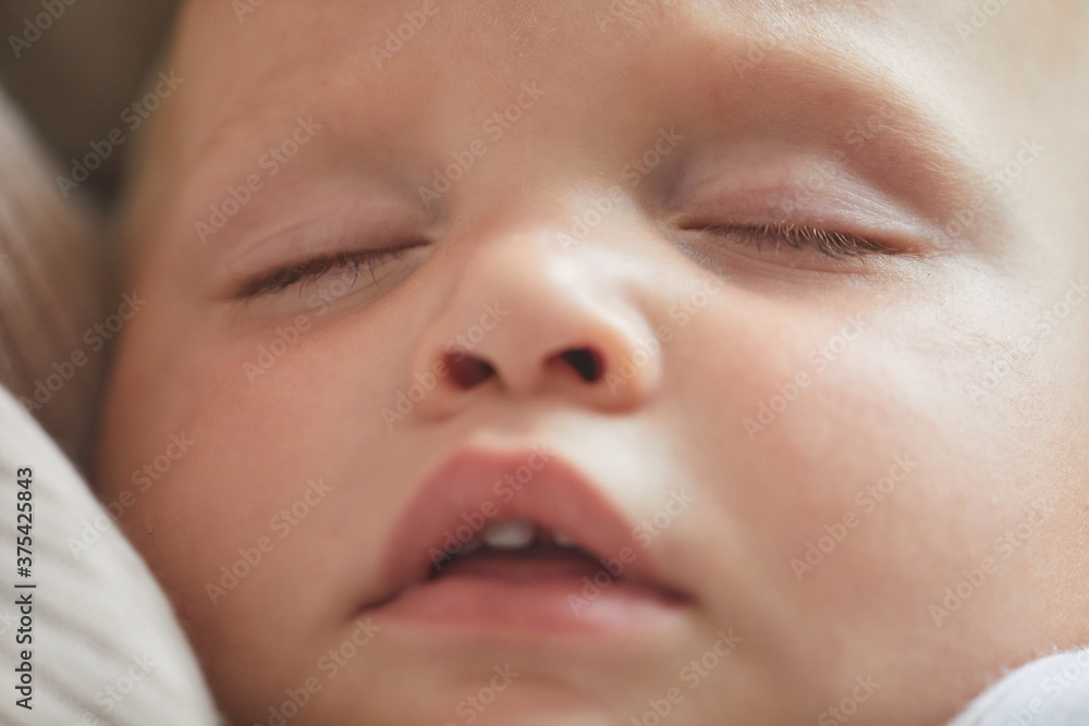 Horizontal close-up headshot of lovely Caucasian baby boy sleeping in his mom's arms Horizontal close-up headshot of lovely Caucasian baby boy sleeping in his mom's arms
