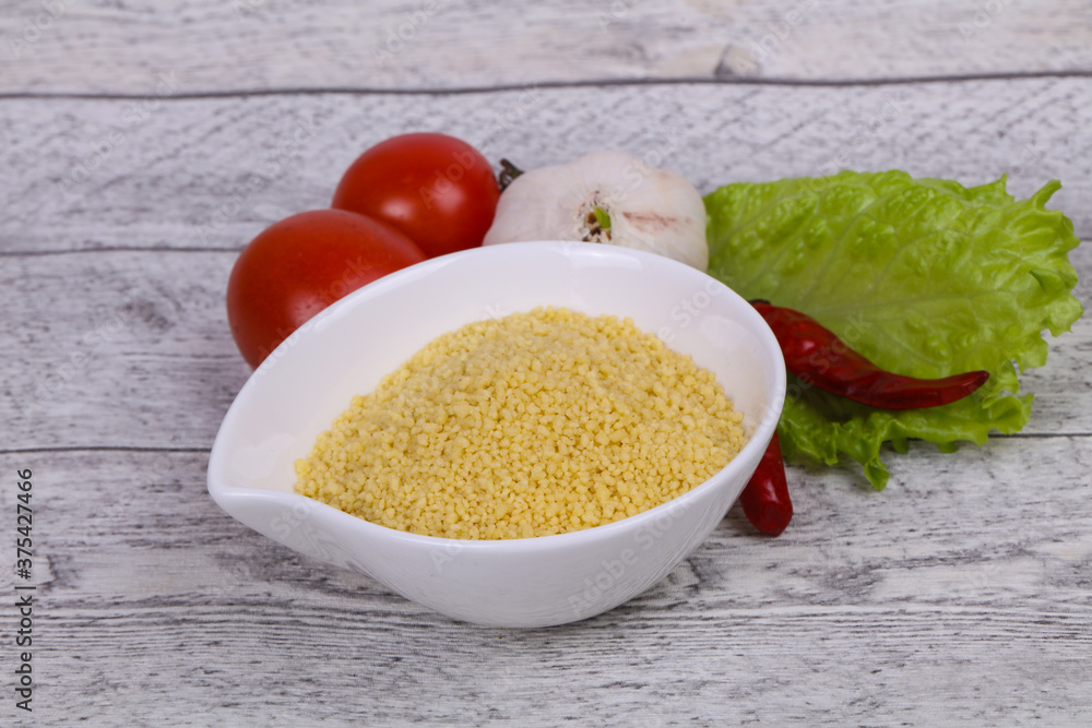 Raw couscous in the bowl served salad leaves, tomato and pepper Raw couscous in the bowl served salad leaves, tomato and pepper