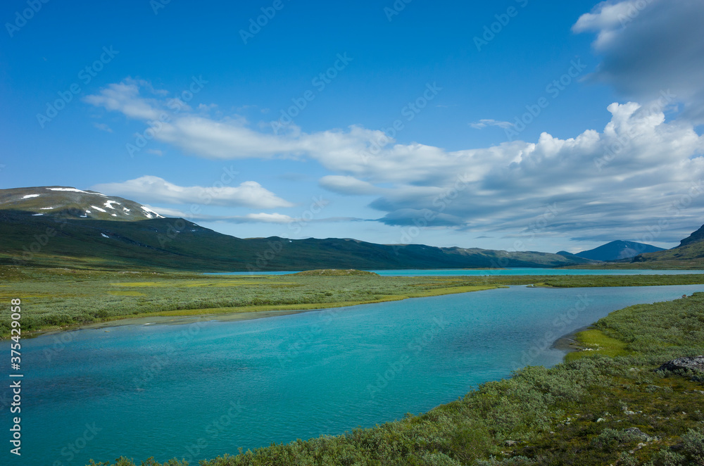 Swedish Lapland landscape. Turquoise water of Lake Alisjavri on Kungsleden and Nordkalottruta Arctic hiking Trail in northern Sweden. Arctic environment of Scandinavia in warm summer sunny day