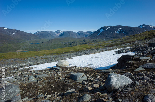 Swedish Lapland landscape with snow and fragile vegetation. Arctic environment of Scandinavia in summer sunny day with blue sky. Nordkalottruta Arctic hiking Trail in northern Sweden photo