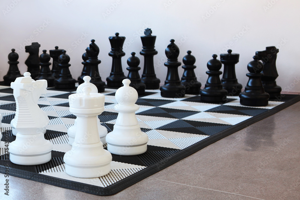 Large chess pieces on the floor. Playing chess on the floor in a visit. Copy of the space.