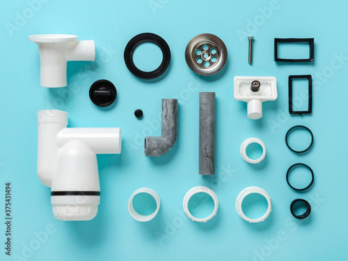 Sink waste water trap parts knolled on a blue background. Knolling style composition of new plastic sink drain with stainless steel strainer. Install, clean and repair of domestic plumbing fixtures.