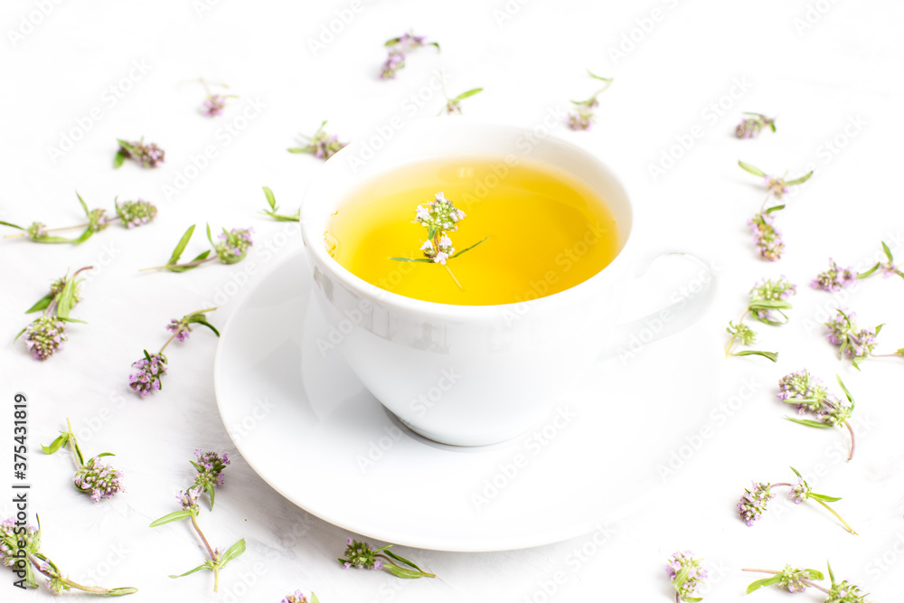 A Cup of tea with thyme flowers on a white background. The view from the top. Concept of folk medicine. Herbal drink. A Cup of tea with thyme flowers on a white background. The view from the top. Concept of folk medicine. Herbal drink.