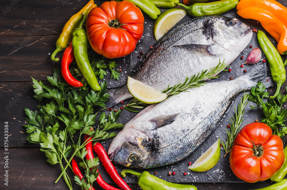 Fresh fish with vegetables, healthy cooking, dorado fish copy space dark background. Fresh fish with vegetables, healthy cooking, dorado fish copy space dark background.